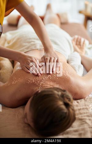 Woman getting deluxe spa treatment including warm seed oil and sea salt scrub Stock Photo