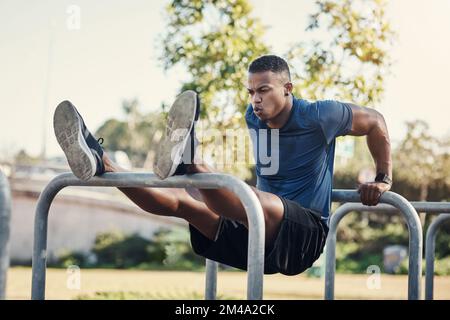 Getting in a couple of dips. Full length shot of a handsome young man doing dips while exercising outside at a calisthenics park. Stock Photo