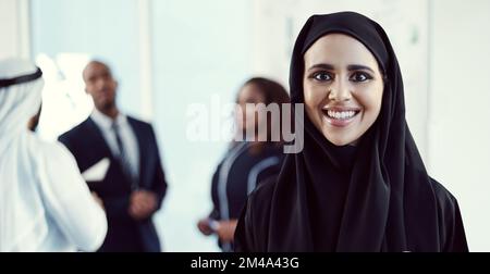 Im motivated to succeed. Cropped portrait of an attractive young arabic businesswoman standing in the office with her colleagues in the background. Stock Photo