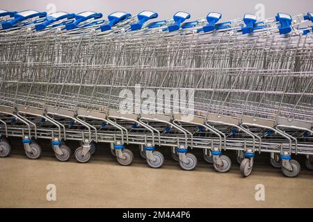 Row of Stacked Supermarket Trolleys. Row of stacked metal supermarket trolleys can be seen in perspective. Large group of shopping carts lined up in r Stock Photo