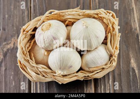 Shallot lies in wicker basket on wooden background Stock Photo