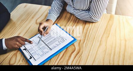 This document requires some careful reading. Closeup shot of two businesspeople going through paperwork in an office. Stock Photo