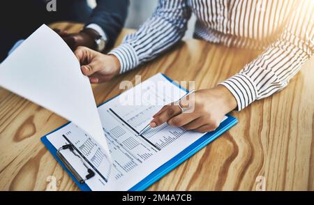 Double-checking all their facts and figures. Closeup shot of two businesspeople going through paperwork in an office. Stock Photo