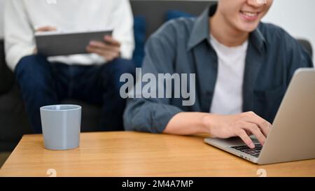 Young Asian male freelancer or college student using laptop computer, typing on keyboard, browsing something on internet. cropped image Stock Photo