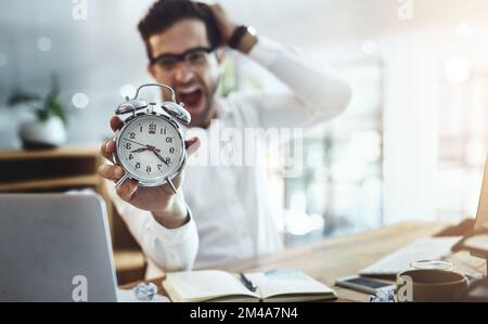 Panic mode. Portrait of a young businessman looking stressed out while holding a clock in an office. Stock Photo