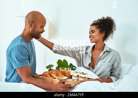 Youre so sweet for bringing me breakfast. an affectionate young couple having breakfast in bed. Stock Photo