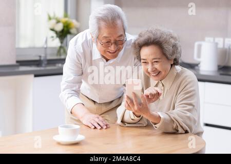 Senior Chinese couple  using smartphone at home Stock Photo