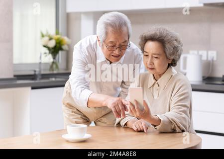 Senior Chinese couple  using smartphone at home Stock Photo