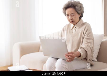 Senior Chinese woman using laptop at home Stock Photo