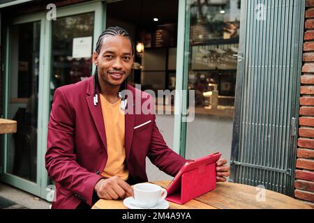 African man drinking a coffee while using a tablet Stock Photo