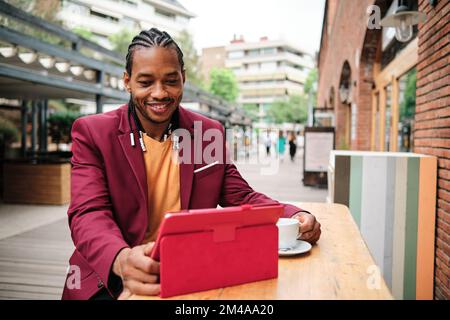 Stylish african man using a tablet in a cafeteria Stock Photo