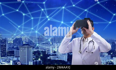 Asian male doctor with a stethoscope using virtual reality with a network city background. National Science Day Stock Photo