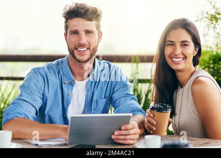 Our smartest tools always accompany us. Portrait of two businesspeople using a digital tablet together outdoors. Stock Photo