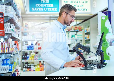 Working the checkout counter. a handsome mature male pharmacist working in a pharmacy. Stock Photo