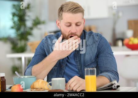 man falling asleep during his breakfast after overtime work Stock Photo