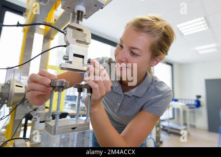 young female technician while machine constructing in a manufacturing plant Stock Photo