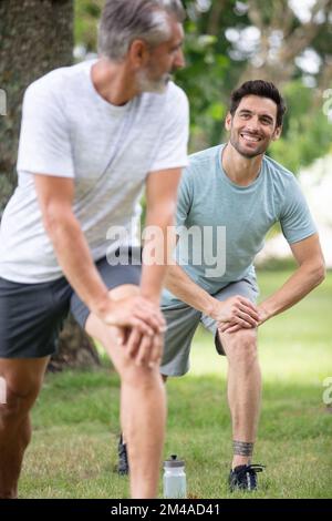 two male runners stretching before workout Stock Photo