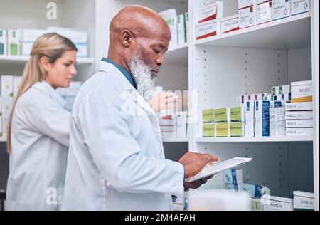 Pharmacy, stock and digital tablet for inventory by man and woman checking medicine and packing shelves. Pharmacist, senior man and online search on Stock Photo