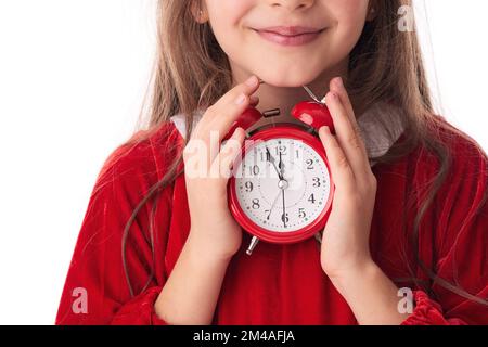 Christmas woman with red alarm clock, smiling girl in red Santa claus dress posing on white background Stock Photo