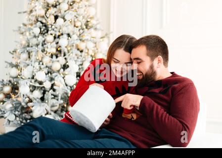 Cheerful man and woman opening a Christmas present Stock Photo