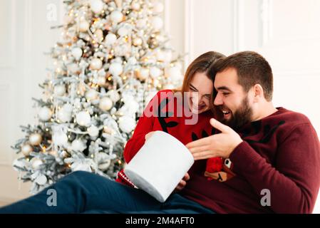 Cheerful man and woman opening a Christmas present Stock Photo
