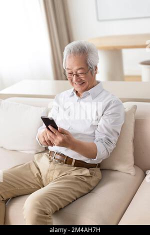 Senior Chinese man using smart phone at home Stock Photo