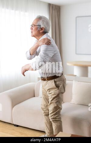 Senior Chinese man suffering from pain on shoulder Stock Photo