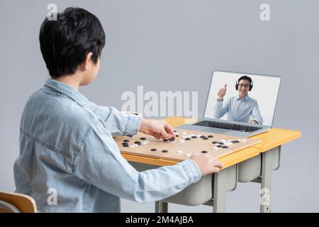 Cute Chinese boy learning to play the game of Go with laptop Stock Photo