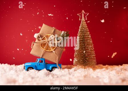 A toy car carries a large gift for the New Year and Christmas on a red background Stock Photo