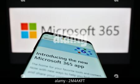 Mobile phone with website of productivity software Microsoft 365 on screen in front of business logo. Focus on top-left of phone display. Stock Photo