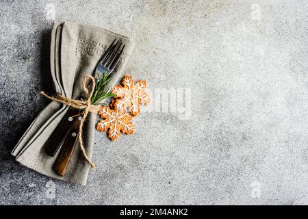 From above table cloth napkin with cutlery near gingerbread cookies setting for Christmas dinner on concrete table on white background Stock Photo