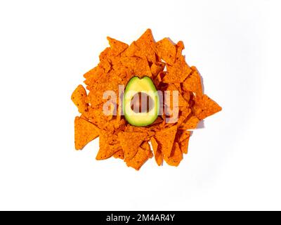 Top view of half of fresh avocado placed on pile of crunchy tortilla chips on white background Stock Photo