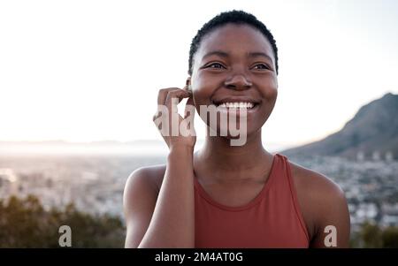 Music, fitness and running with a sports black woman outdoor in nature for a workout or exercise. Health, wellness and training with a female runner Stock Photo