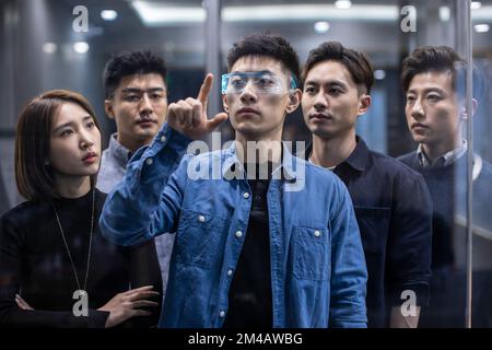 Confident Chinese designers checking futuristic glasses Stock Photo