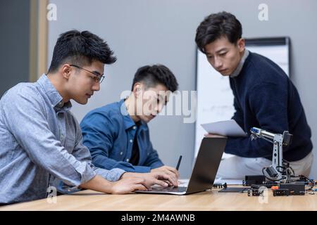 Confident Chinese designers checking a robotic arm Stock Photo