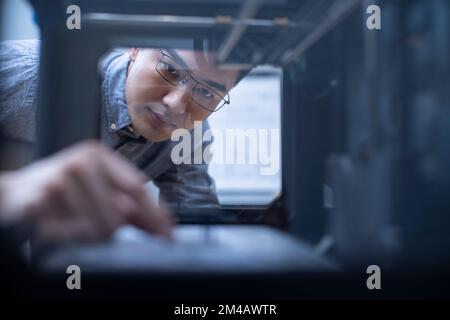 Confident Chinese designer using a 3D printer Stock Photo