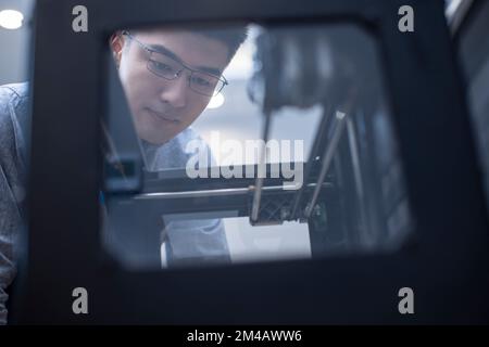 Confident Chinese designer using a 3D printer Stock Photo