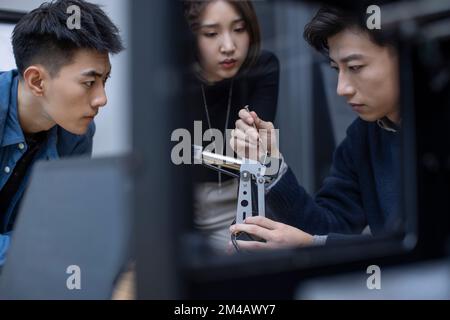 Confident Chinese designers checking a robotic arm Stock Photo