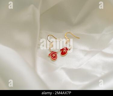 A closeup shot of Christmas mittens earrings on a white background Stock Photo