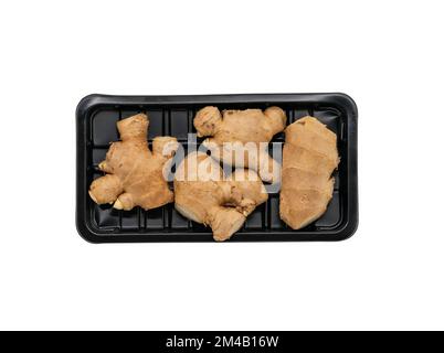 Aged fresh ginger in a black plastic tray for sale in supermarket, flat lay ginger with tray, isolated image on white background. Stock Photo
