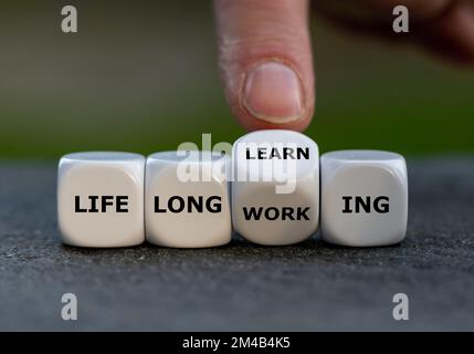 Hand turns dice and changes the expression 'life long working' to ' life long learning'. Stock Photo