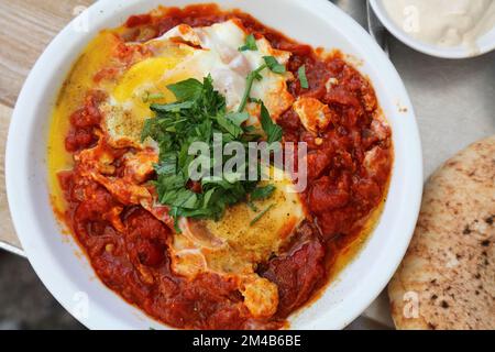 Israeli cuisine. Shakshuka lunch - poached eggs in spicy pan fried tomatoes. Stock Photo
