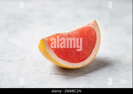 Juicy red grapefruit slice on a blue background close up. Concept healthy and diet food. Macro and copy space. Stock Photo