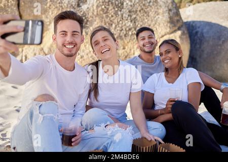 Phone, drinks and friends taking a selfie on beach enjoying summer holiday, vacation and weekend getaway. Travel, smartphone and couple of men and Stock Photo
