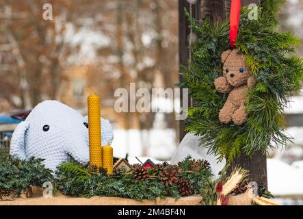 Beautiful handmade Christmas garlands or wreaths with teddy bear, displayed at a street market in winter Stock Photo