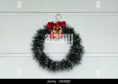 Christmas wreath decoration is hanging on the white wall as background Stock Photo