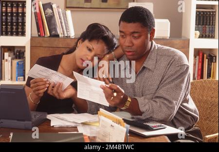 African-American couple sitting at a table paying their bills Stock Photo