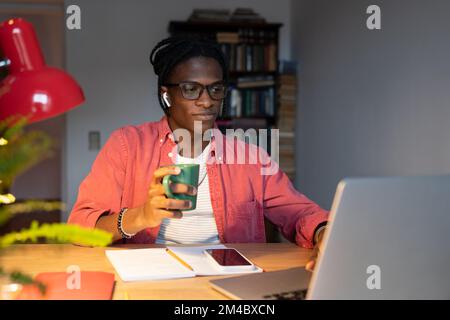 Young African millennial guy student using laptop for remote learning, studying online at home Stock Photo