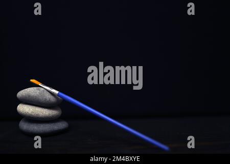 paint stones, blue brush and acrylic colors on black background Stock Photo