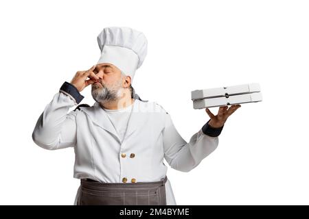 Portrait of bearded man, restaurant chef in uniform holding pizza boxes isolated on white background. Delicious Italian taste Stock Photo